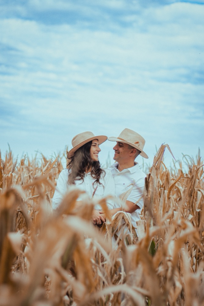 Aymi y Juan con sombreros en un campo de maíz